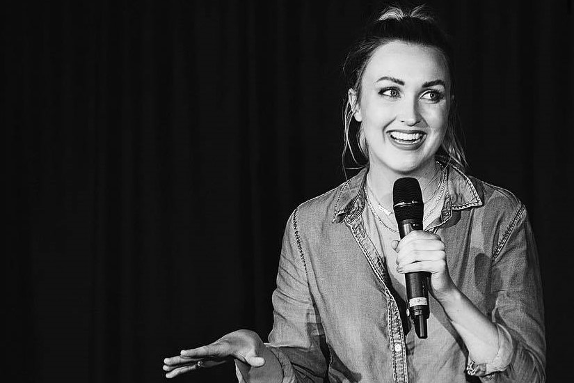 Joanna smiles while talking into a microphone.