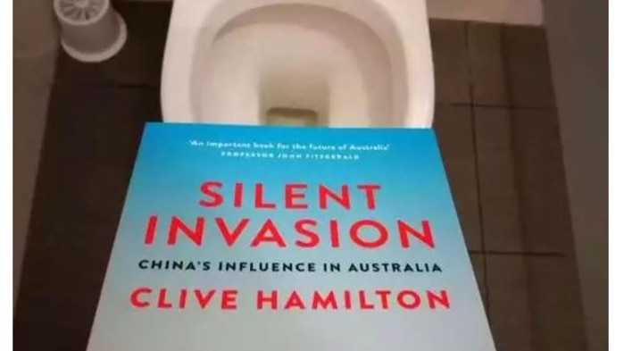 The book Silent Invasion is shown held above an open toilet