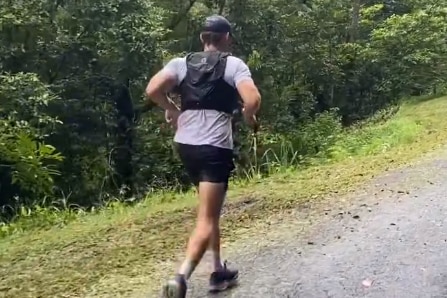 A man in a gray shirt running up a steep hill