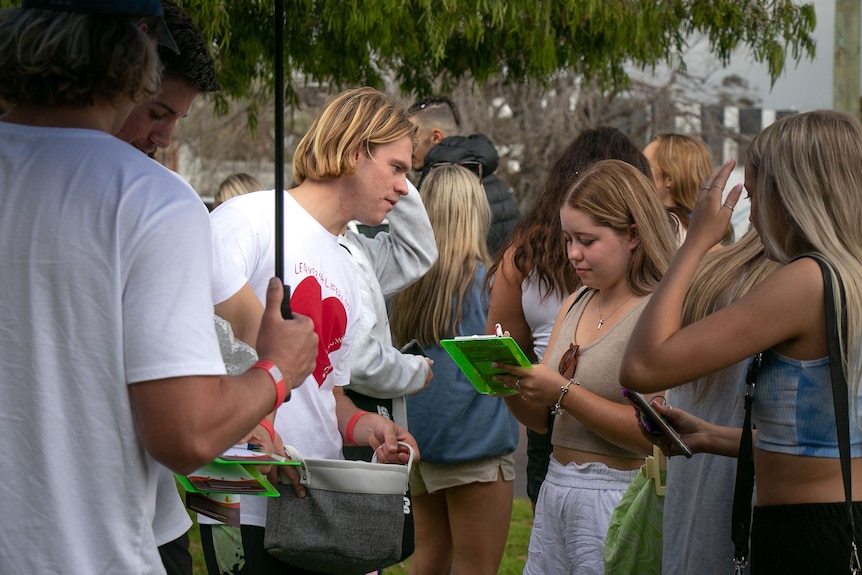 A young man with a clip board talks to a group of young women