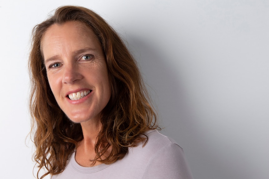 Closely cropped image of a woman with shoulder-length auburn hair, smiling.