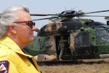A firefighter stands in front of an Army helicopter.
