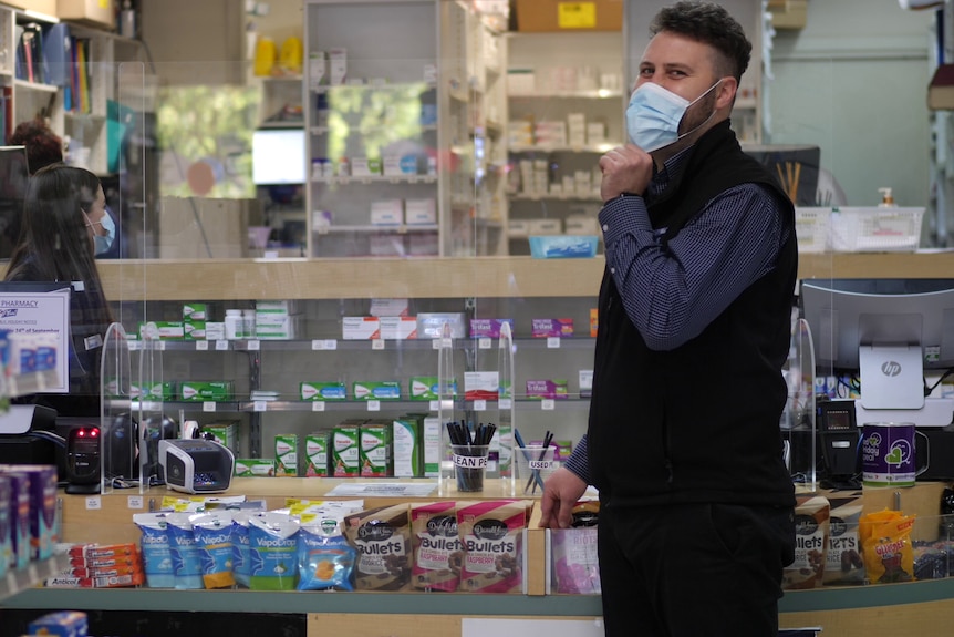 A man wearing a mask in a pharmacy.