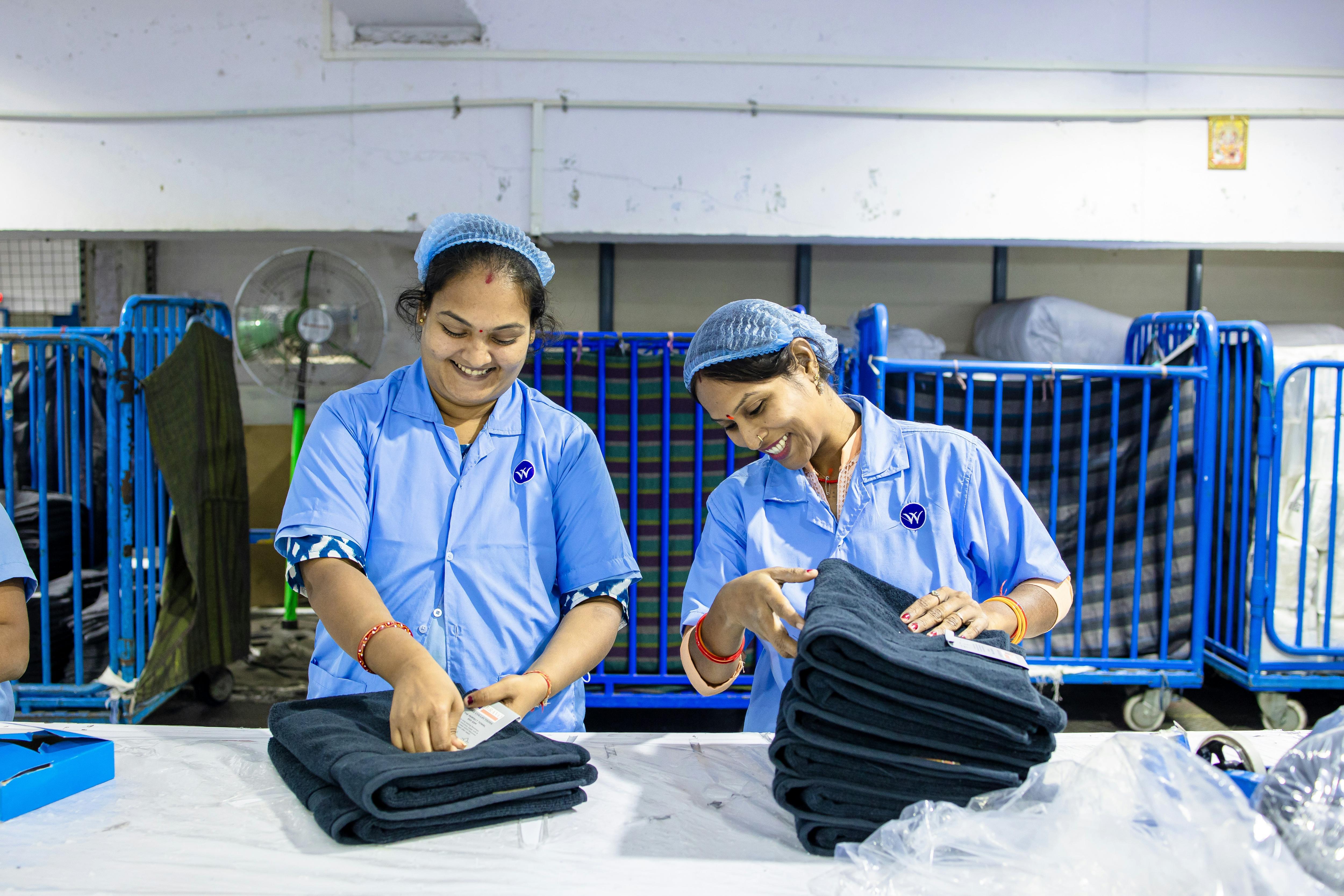 two women wearing uniforms and handling folded clothing 