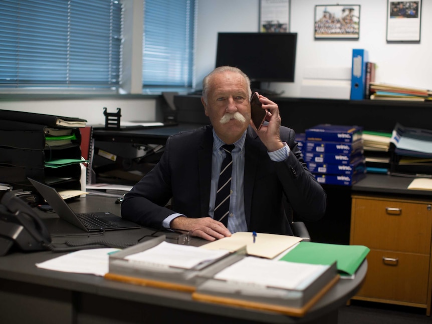 David sits in his office on his mobile phone.