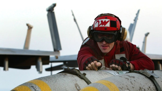 Arms deals: A USS Kitty Hawk crewman wheels 1,000 pound JDAM guided bombs cross the flight deck of the aircraft carrier in the Gulf