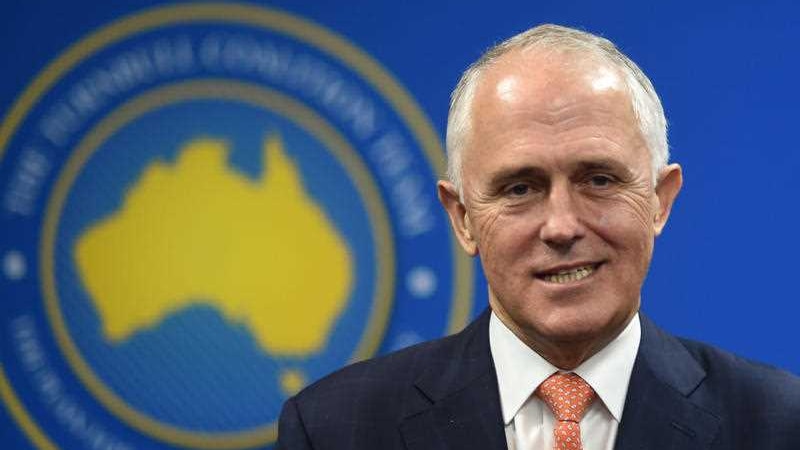 Prime Minister Malcolm Turnbull stands in front of a blue background.