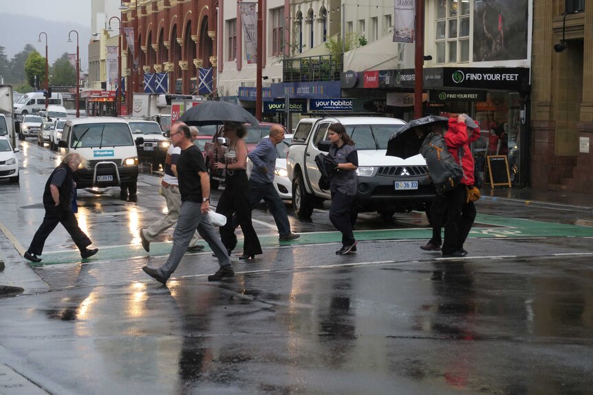 Pedestrians cross a rainy street in Hobart