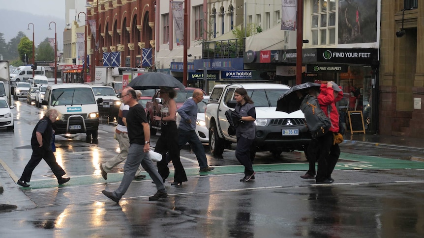 Pedestrians cross a rainy street in Hobart