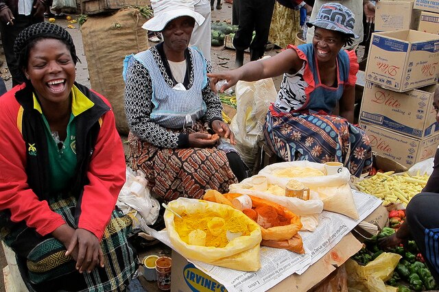 Female vendors joke as they sit on the ground at their stall in the Mbare markets
