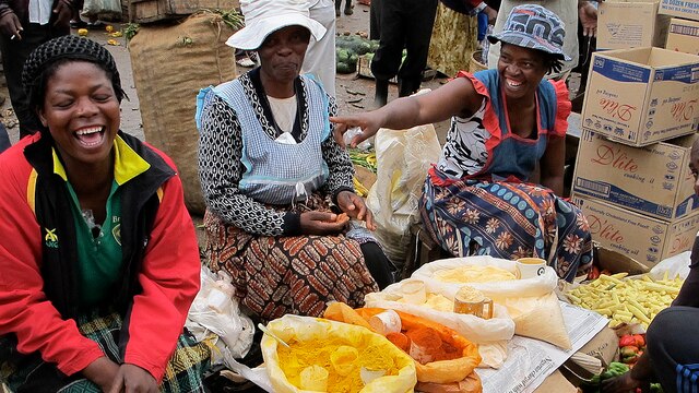 Female vendors joke as they sit on the ground at their stall in the Mbare markets