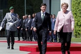 German Chancellor Angela Merkel is walking next to President Volodymyr Zelenskiy, with a military personal walking behind them