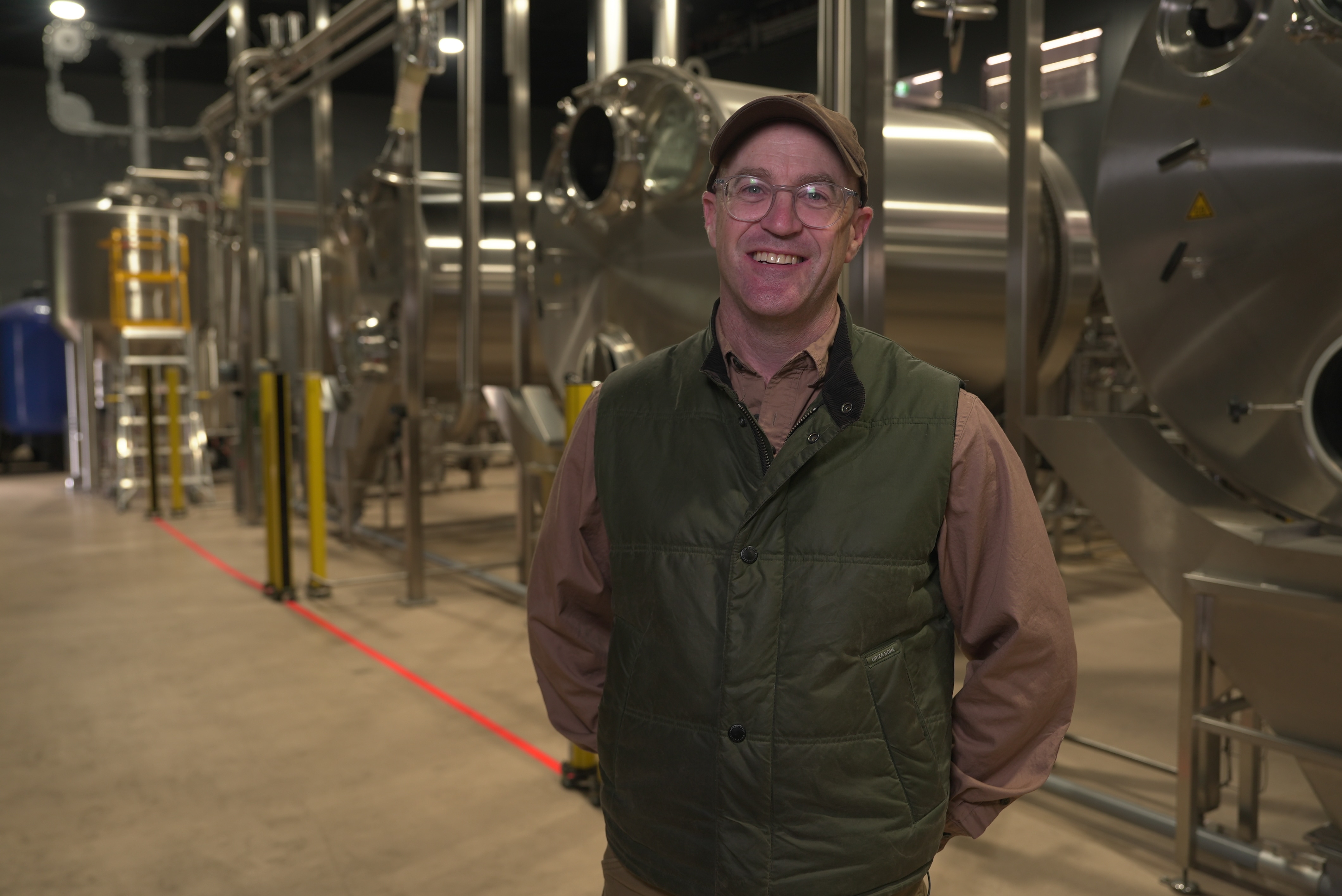 A man standing in front of distilling machinery.