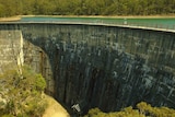 A large dam with blue-green water held back behind a massive wall