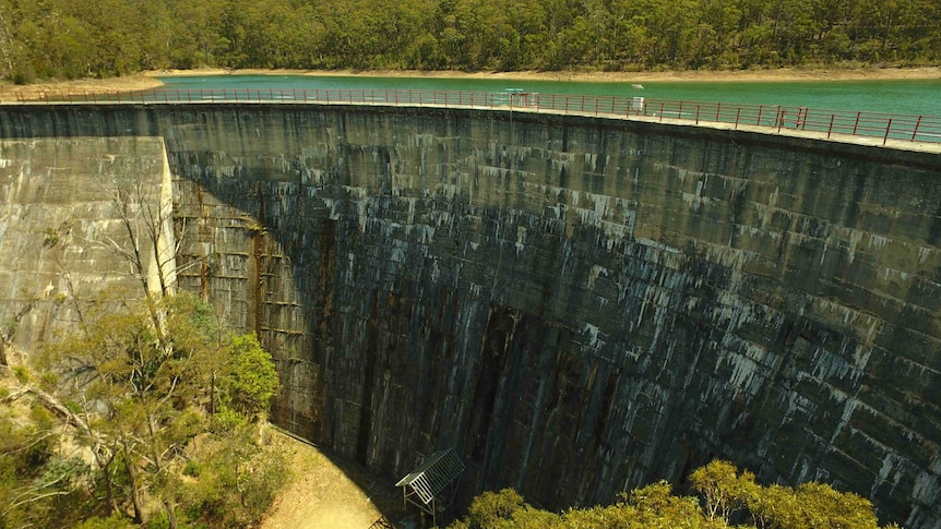 A large dam with blue-green water held back behind a massive wall