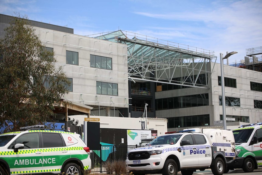 A wide shot showing the mangled metal and glass wreckage of a roof hanging on top of a building at Curtin University.