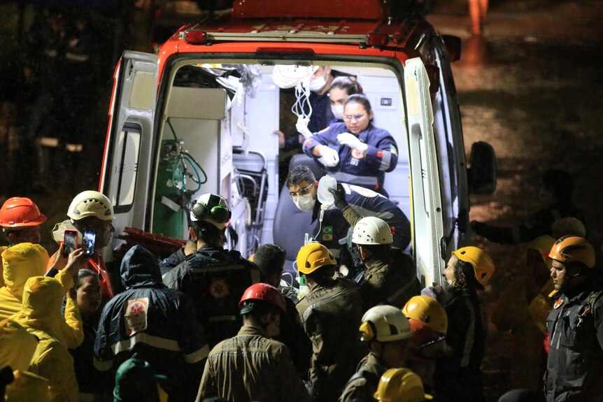 Rescue workers stand outside an ambulance. 