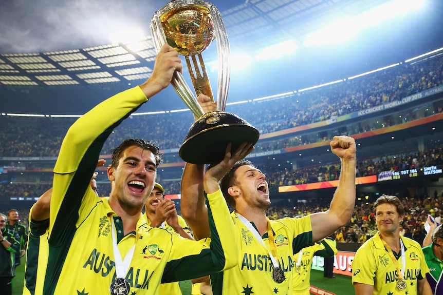 Two men lift a cricket trophy after winning a World Cup final