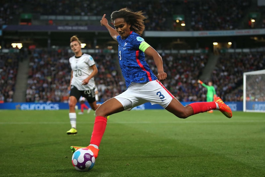 French defender Wendie Renard is shown about to kick the ball hard during a football match.