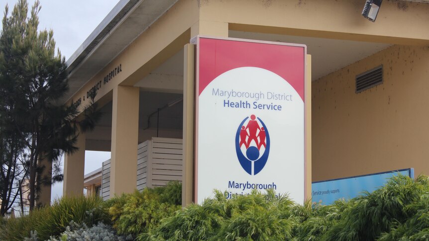 A building with a red and blue sign in front that reads Maryborough District Health Service. 