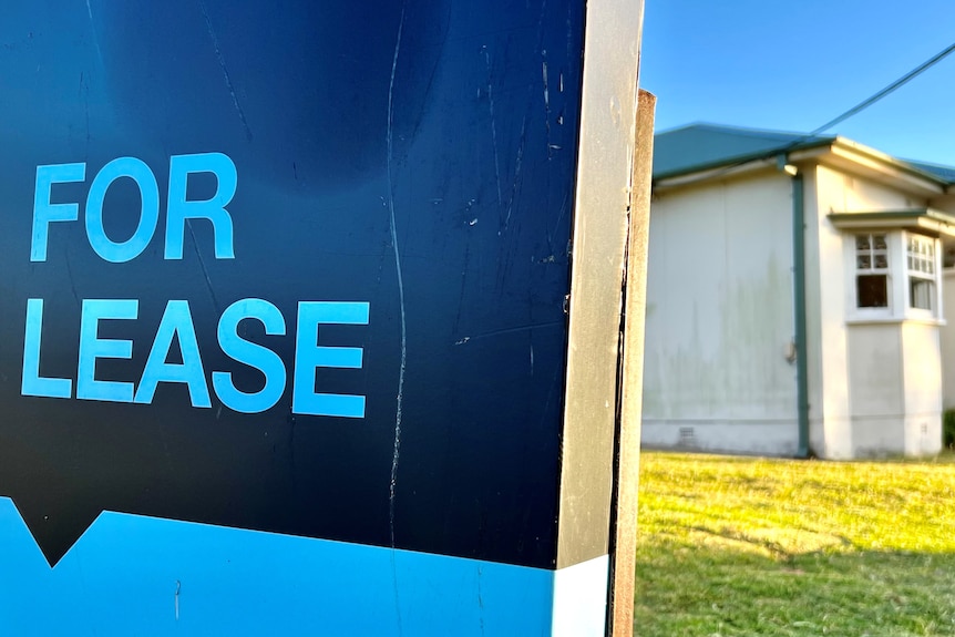 A blue 'for lease' sign outside of a house.