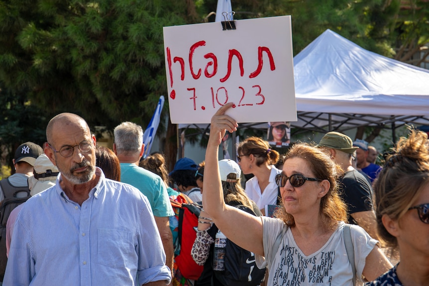 A woman holds up a sign with red writing.
