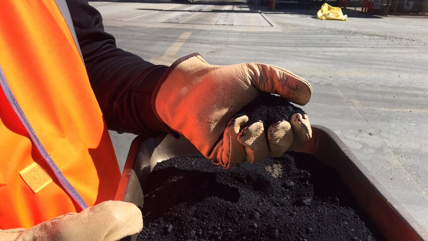 A gloved hand holding the asphalt.