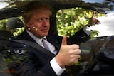 Boris Johnson gives a thumbs up sign while sitting in his car.