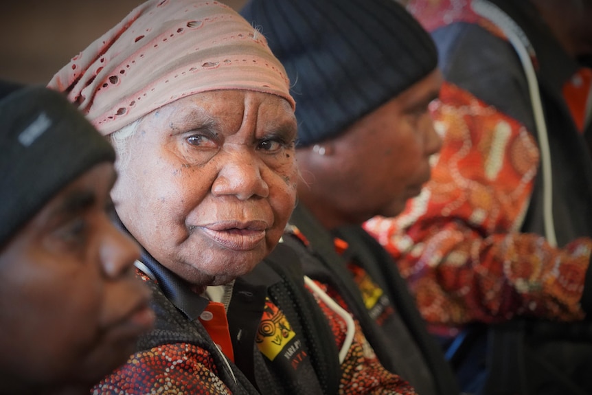 Elderly woman turns her eyes to the side to look at camera with bandana on head