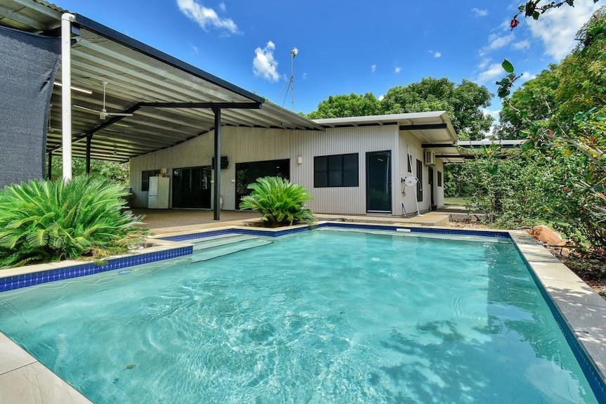 An outdoor pool next to a white dwelling.