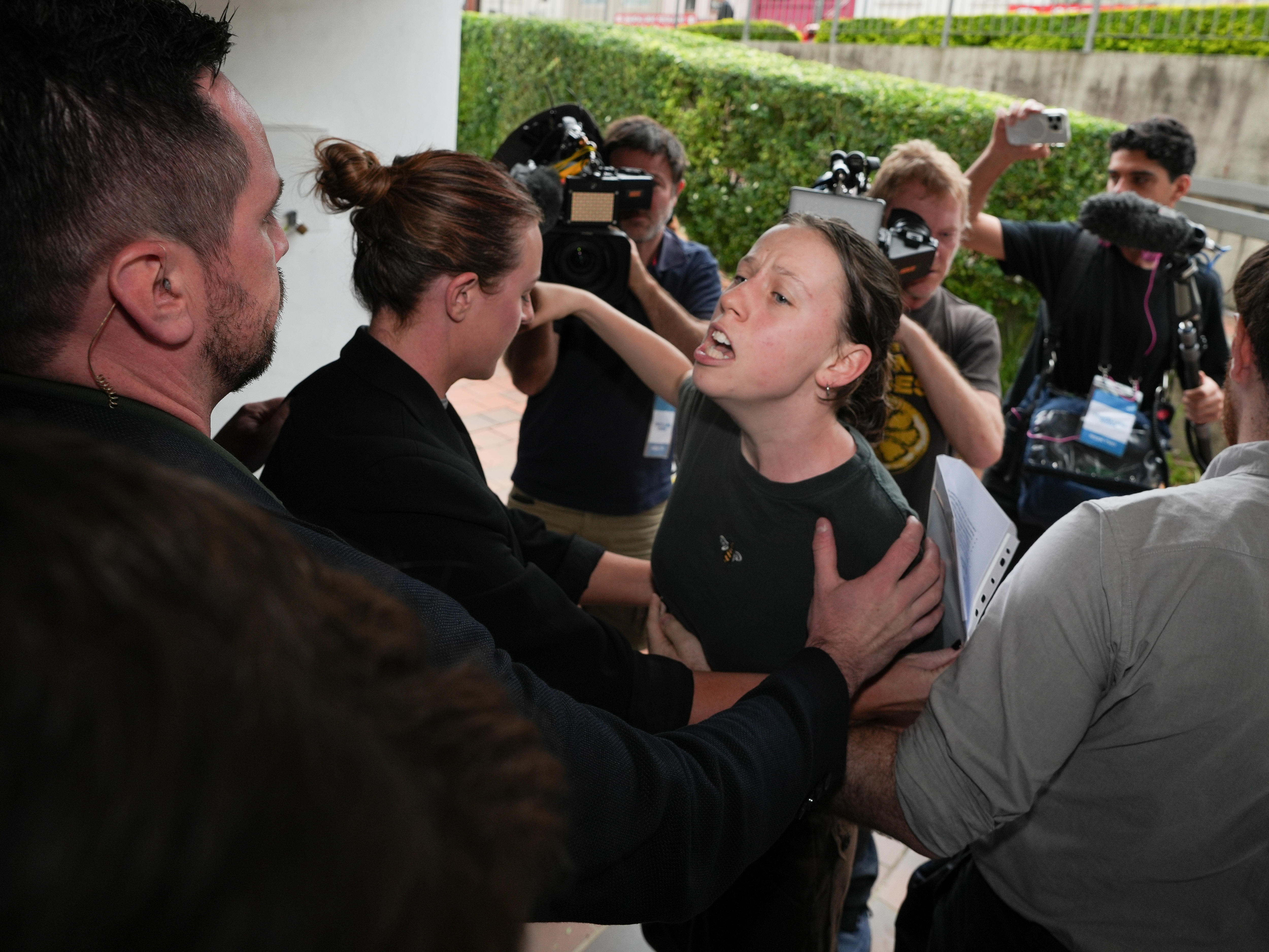 a women shouts, she is surrounded by security and camera men