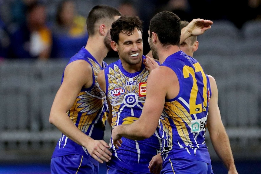 Four West Coast Eagles AFL players embrace as they celebrate a goal against the GWS Giants.