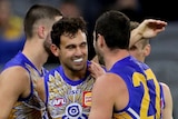 Four West Coast Eagles AFL players embrace as they celebrate a goal against the GWS Giants.