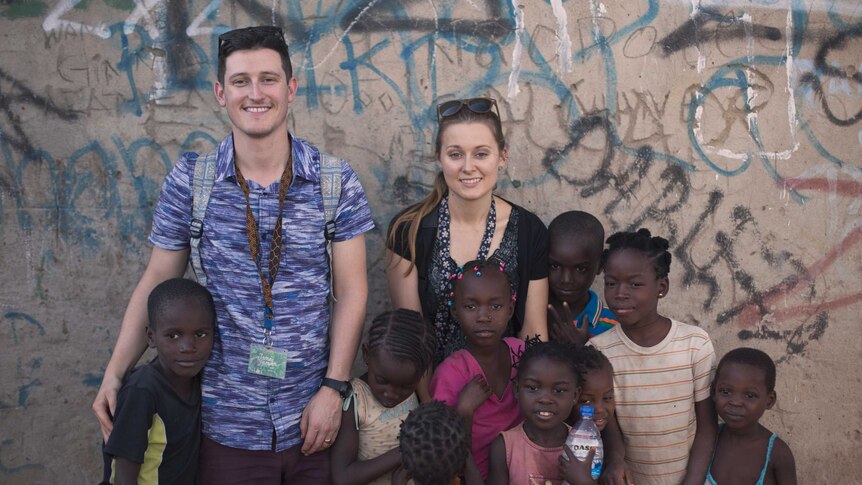 Couple standing in front of wall with eight young African children