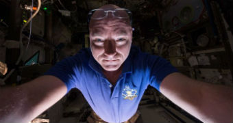 Scott Kelly holds the camera in front of him and takes a selfie with his spectacles on his head.