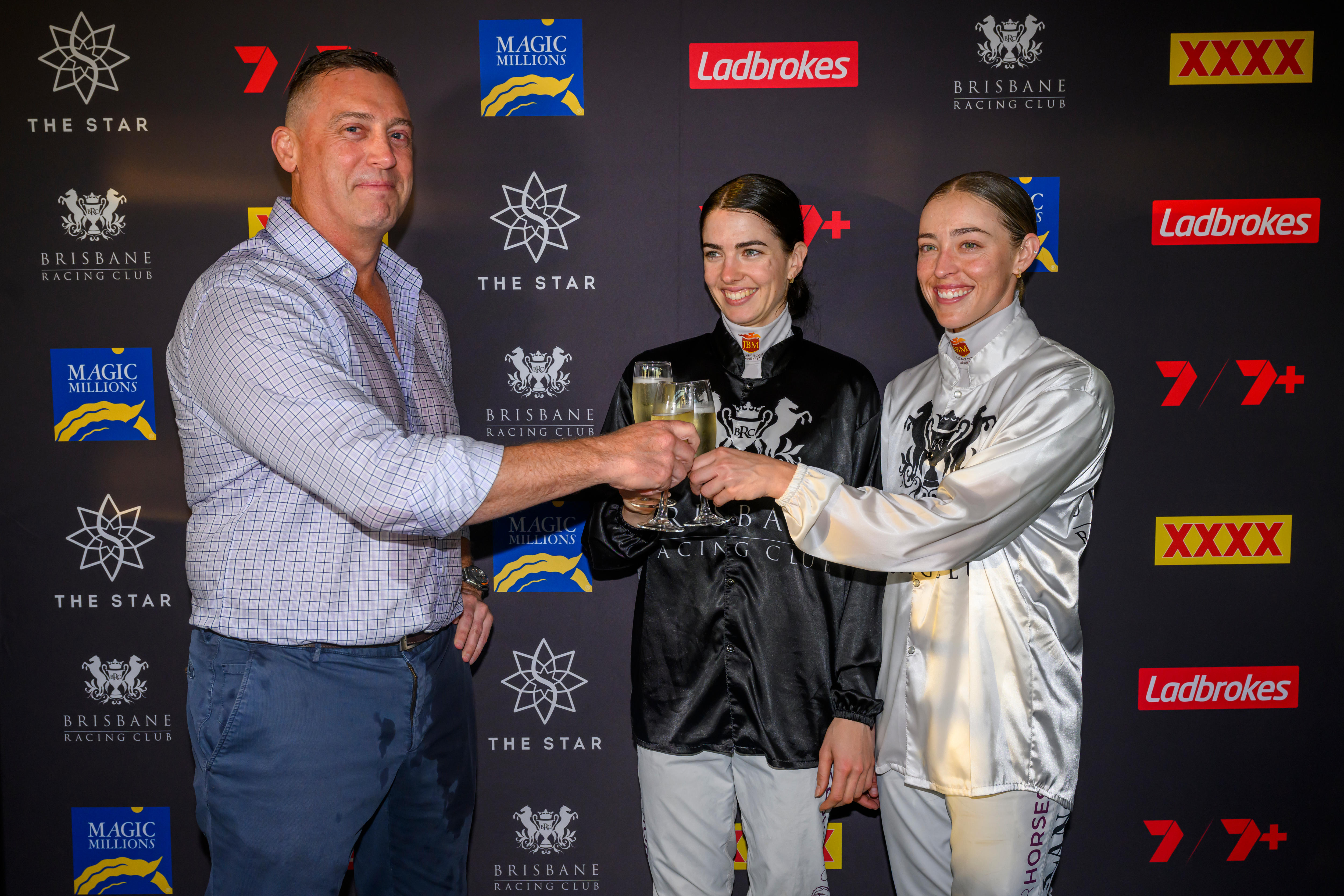 Um treinador de cavalos e dois cavaleiros comemoram suas vitórias.