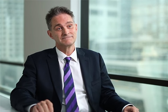 Graeme Cowan, wearing a suit, sits in front of a window.