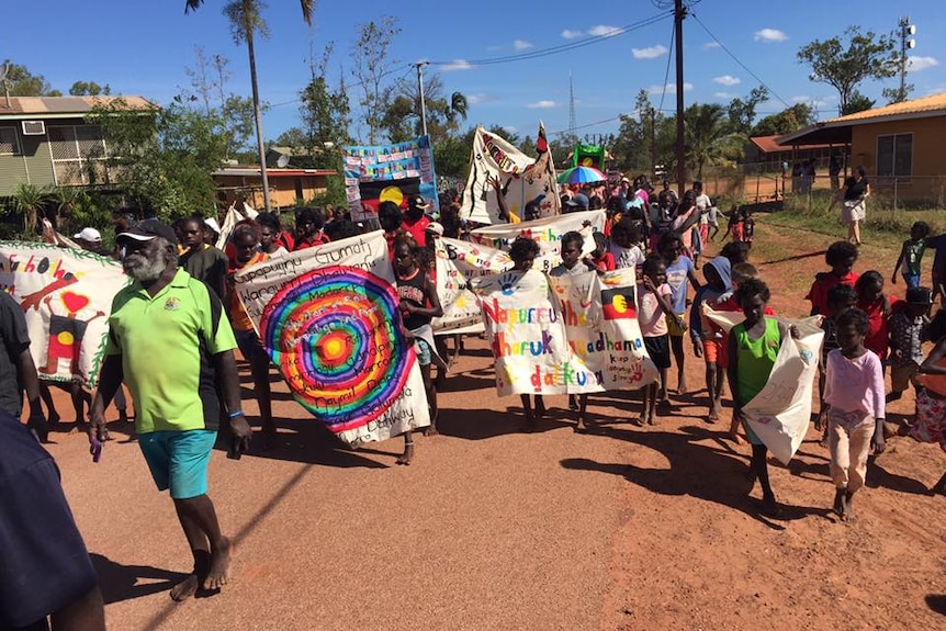 Ramingining locals march with colourful painted banners in celebration of NAIDOC week