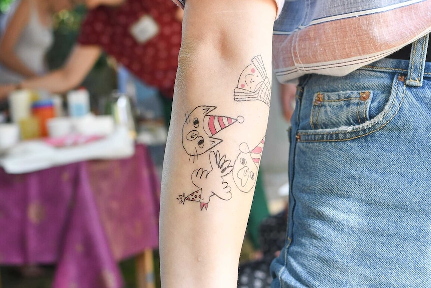 Woman's arm with childish drawing tattoos
