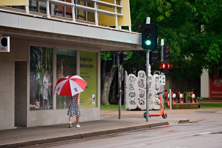 A woman walking with an umbrella through the Darwin CBD.