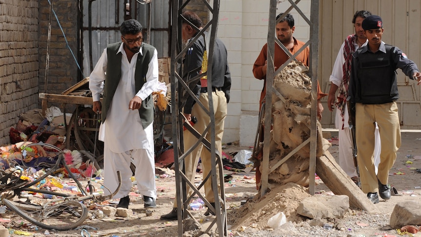 Pakistani security officials examine the site of the bomb explosion.