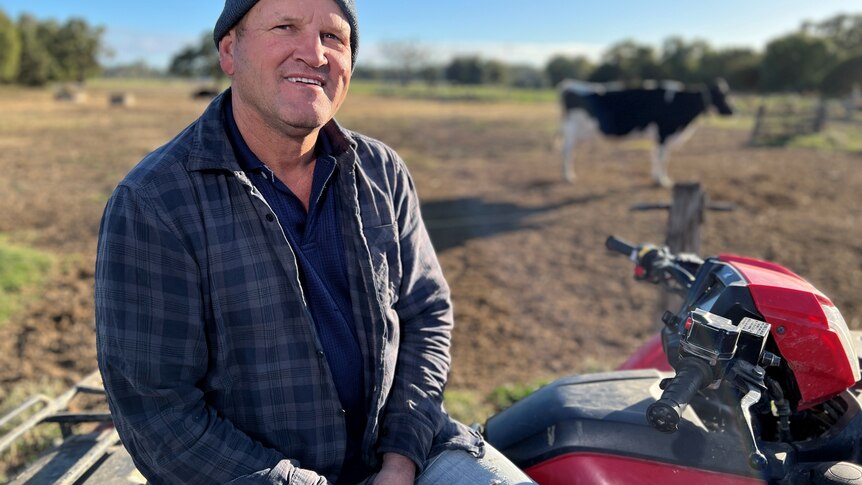 man sitting on a quad bike in front of cow
