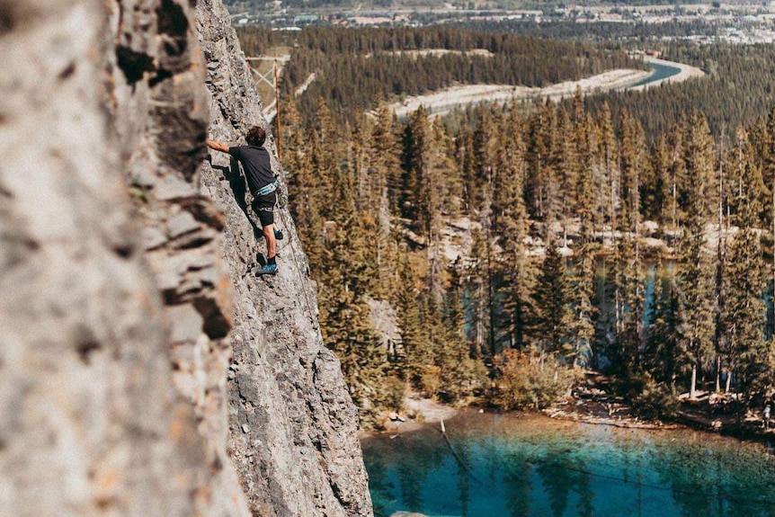 Scott Murphy escalade une paroi rocheuse au-dessus d'un lac