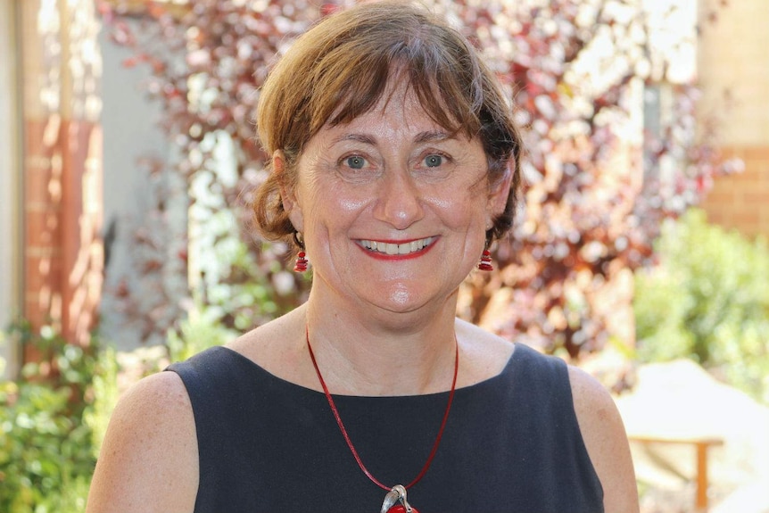 Margaret Ingleton standing in a building courtyard on a sunny day.