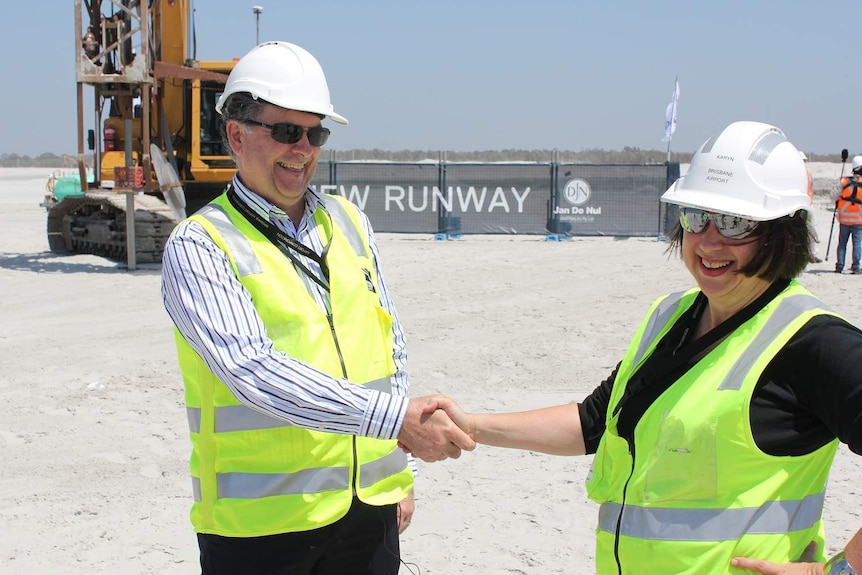 Paul Coughlan shakes the hand of a woman on-site during the construction of Brisbane airport's new second runway.