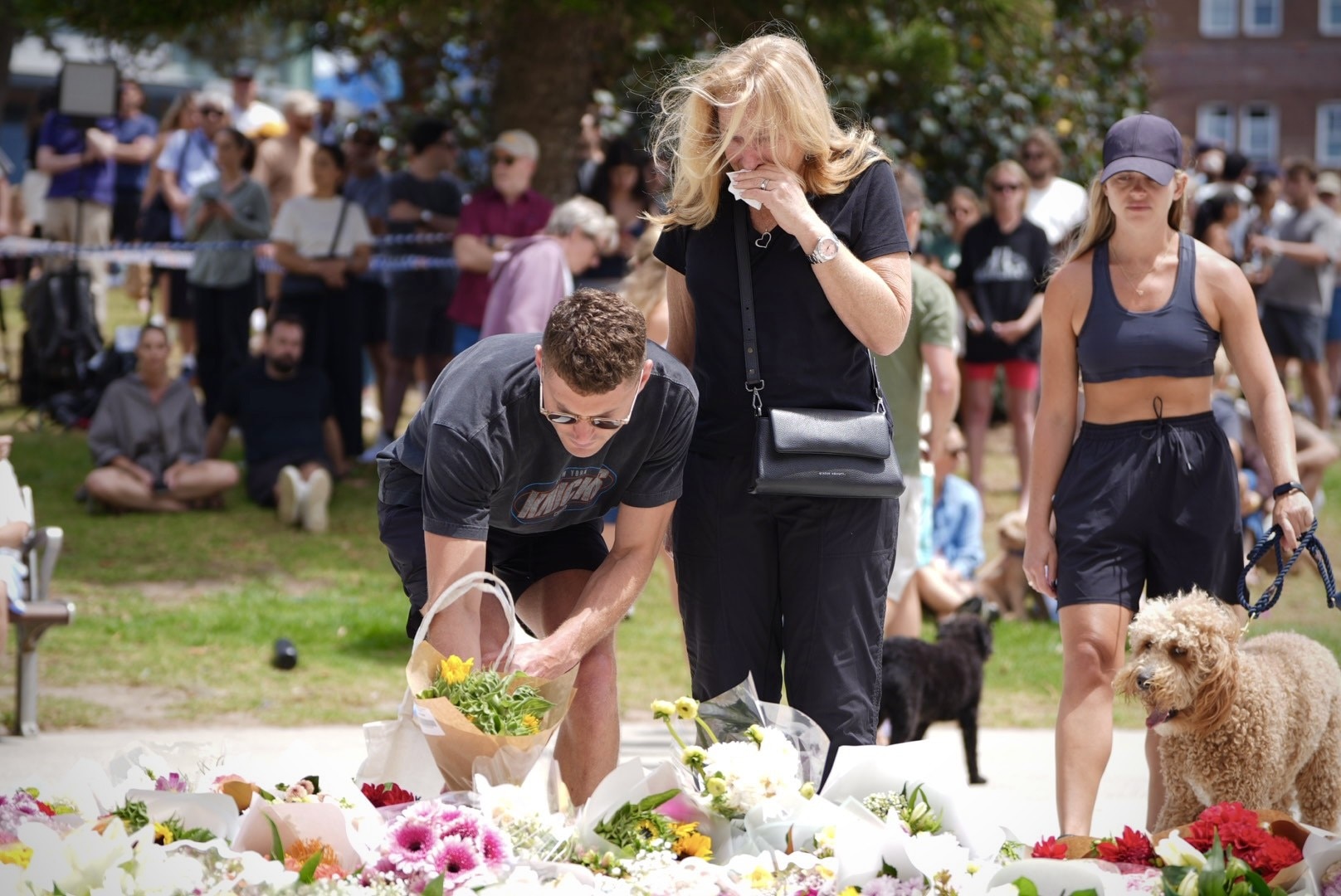 People gather to lay flowers at scene of Bondi Beach shooting.