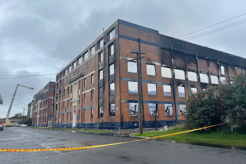 Two fire-gutted warehouse buildings with a fire truck in the background.