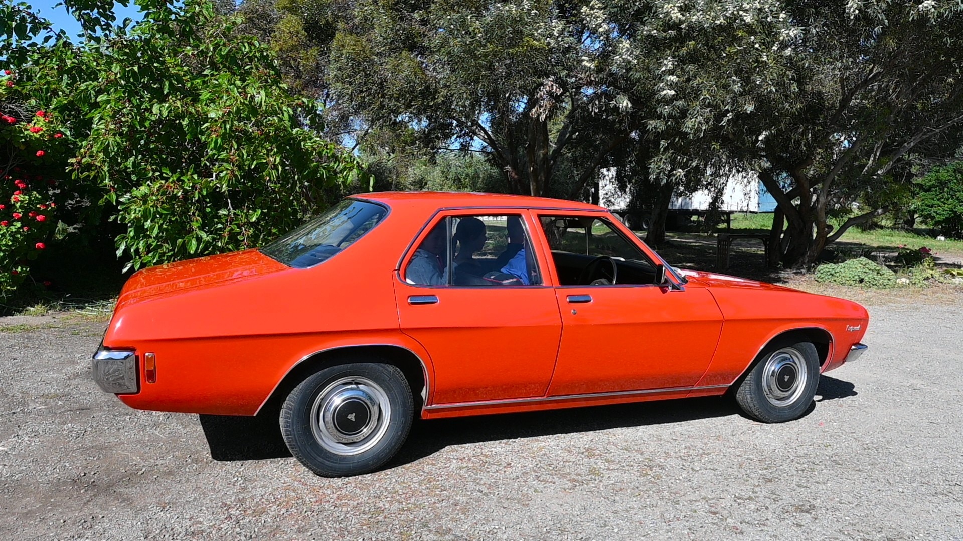 A red Holden Kingswood car, seen from the side. It is parked outside.