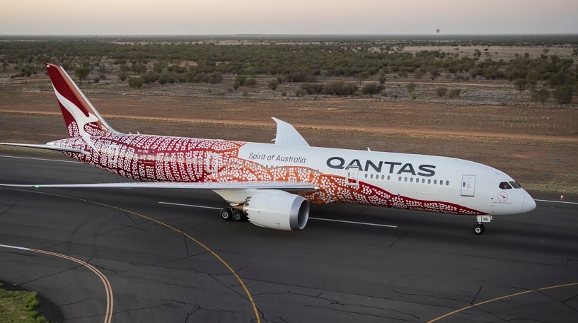 The Qantas Dreamliner featuring indigenous artwork, on the tarmac at Alice Springs at sunrise.