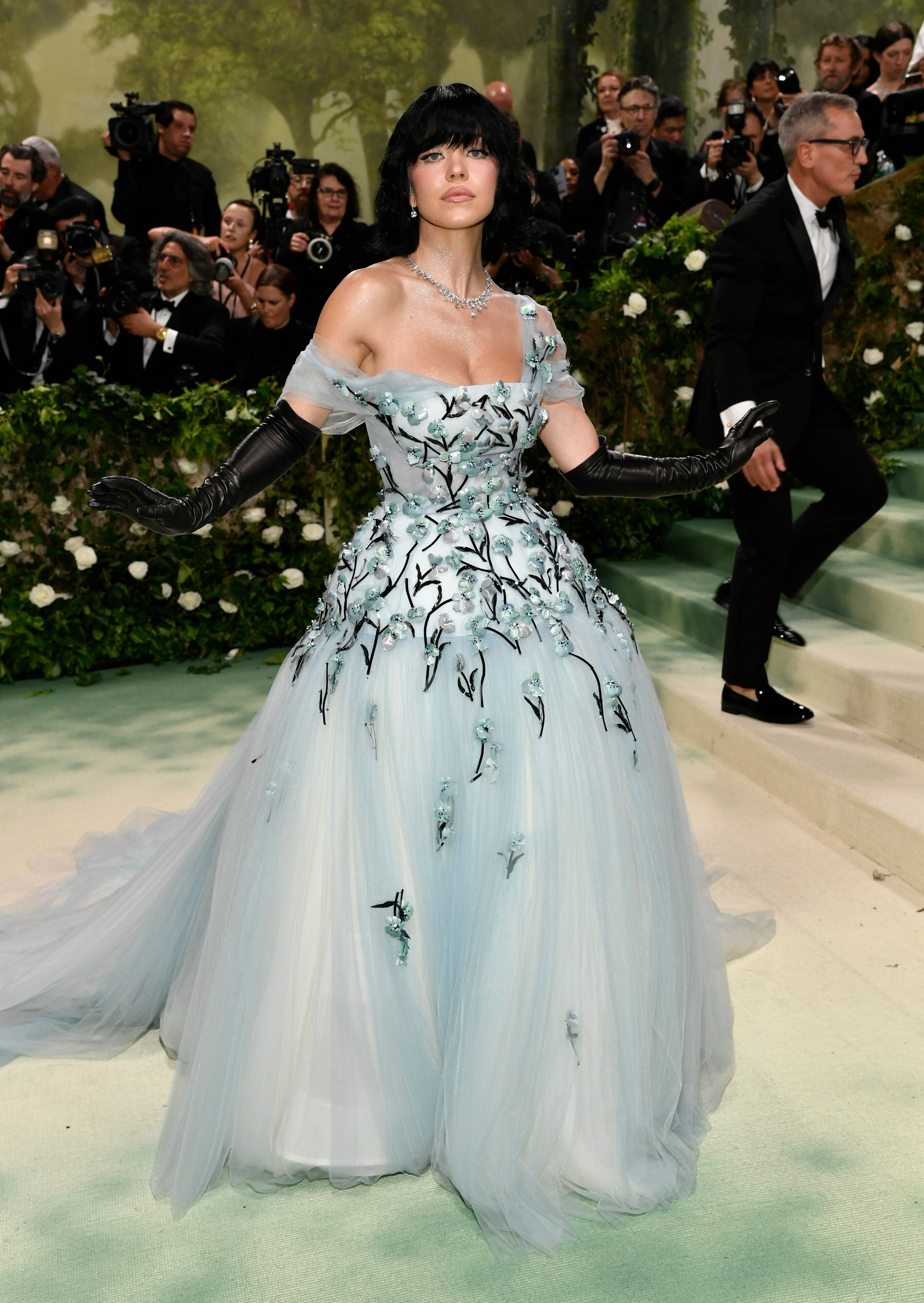 Sydney Sweeney wearing a pale blue tulle dress with silky blue and black flowers, black gloves and black hair